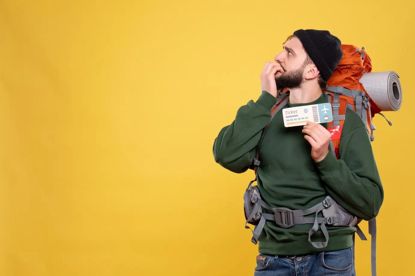 Draufsicht auf ein Reisethema mit einem verwirrten jungen Mann mit Rucksack, der ein Ticket hält.