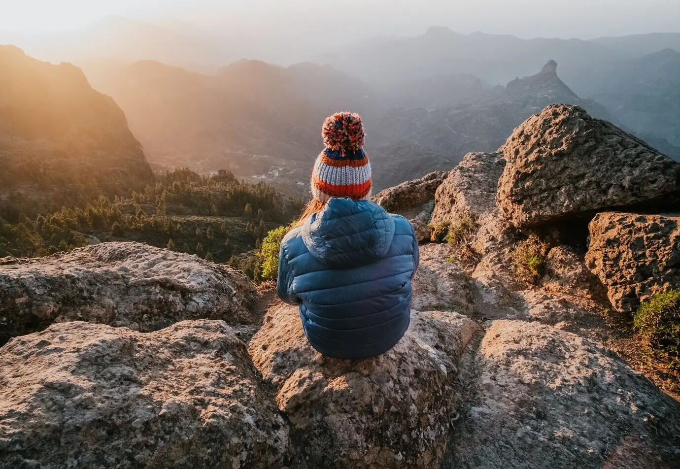 Ein fesselnder Blick von oben auf felsige Berge und eine rückwärts sitzende Frau.